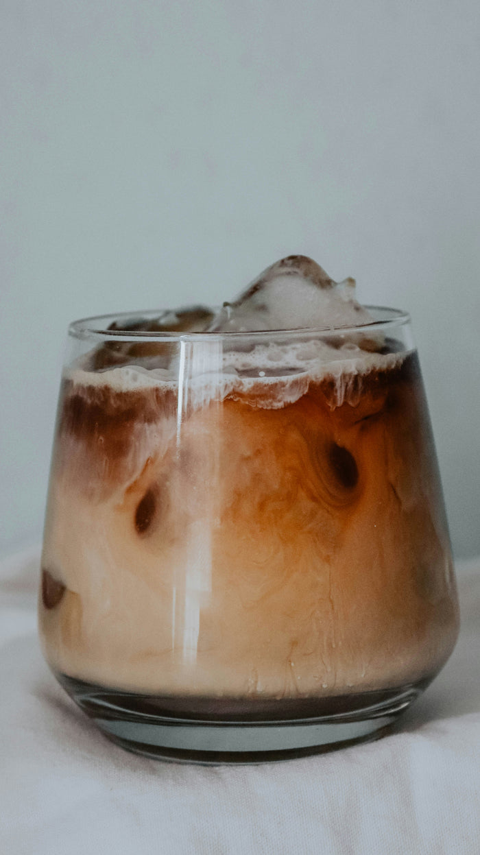 Glass of iced dirty chai in a clear glass, filled with ice cubes and layers of milk, chai and espresso